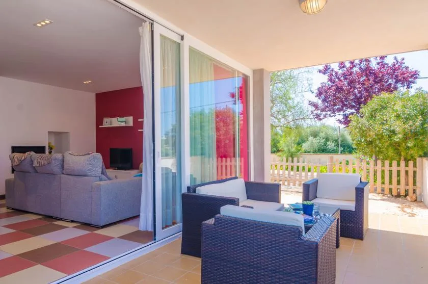 A covered patio with outdoor seating opens onto a garden through sliding glass doors.