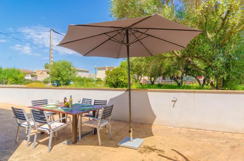 An outdoor dining table with seating sits beneath a large patio umbrella.