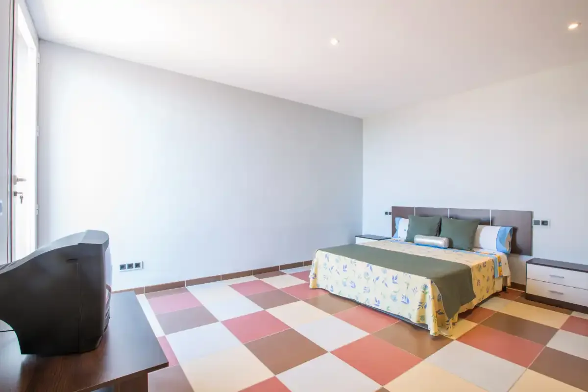 A bedroom with a bed and a colorful checkerboard floor.