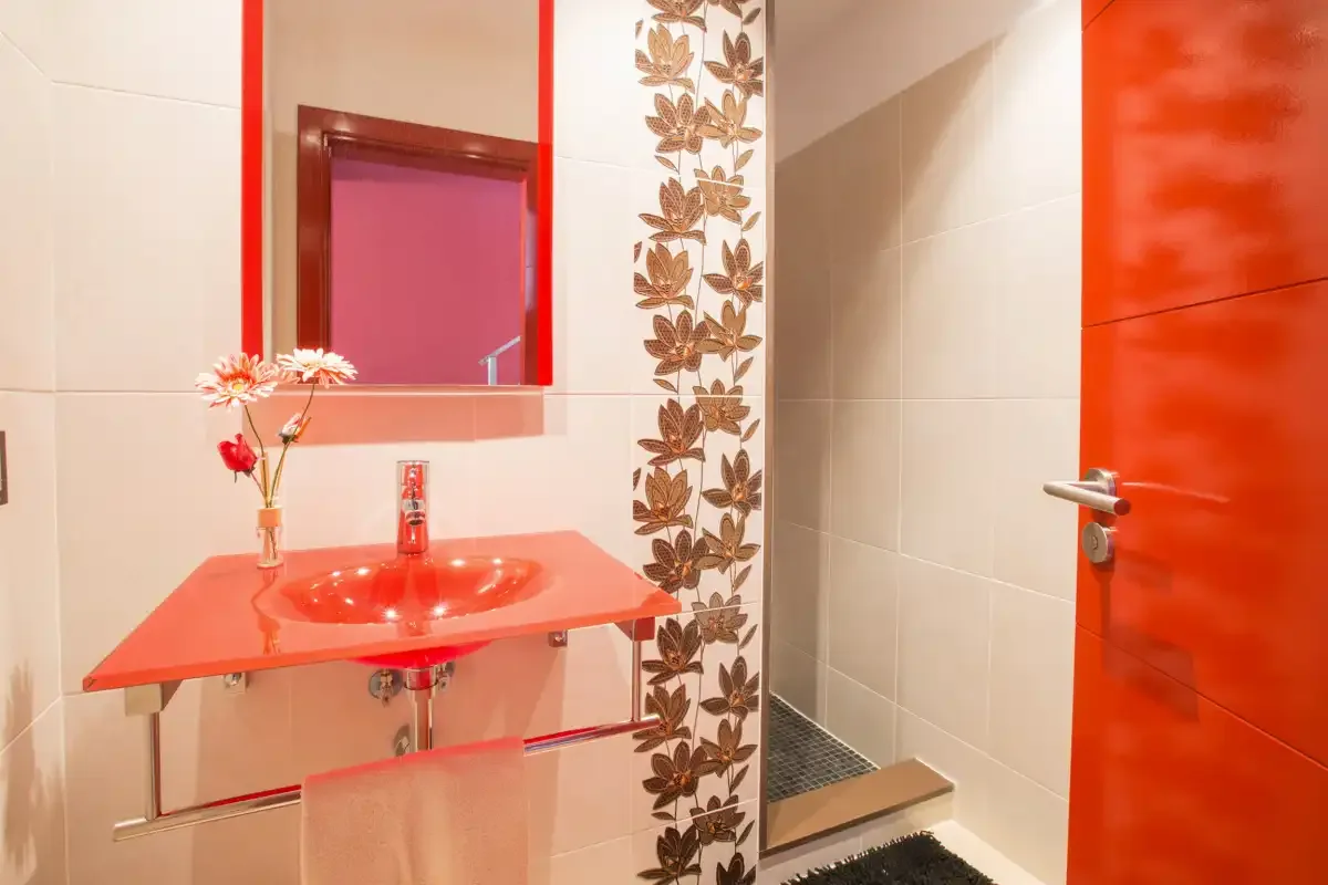 A tiled bathroom with a red vanity and a shower.