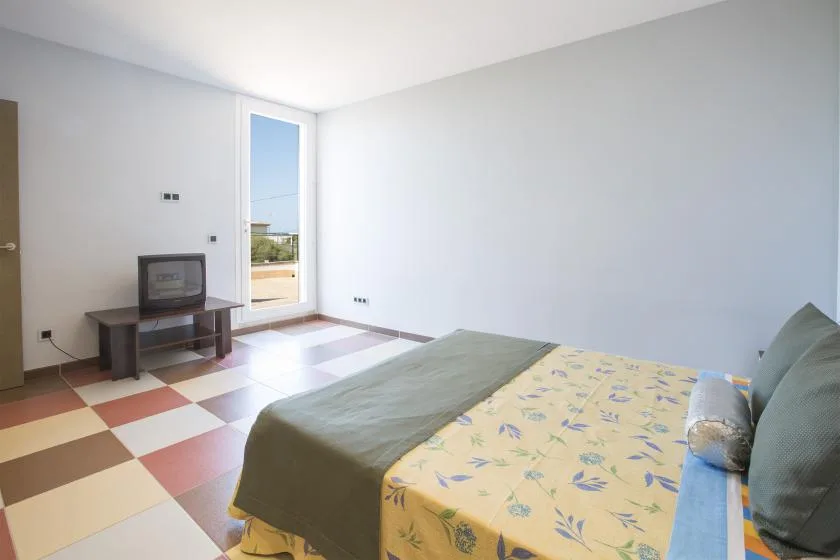 A bedroom with a bed, television, and a bright glass door.