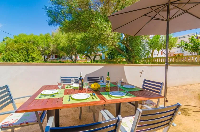 An outdoor dining area with a set table beneath a large patio umbrella.