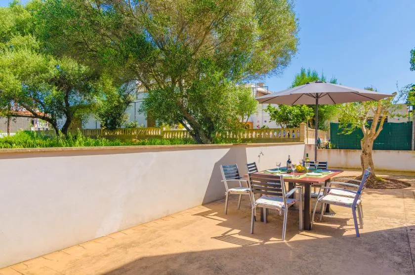 An outdoor dining area with a table and chairs beneath a large umbrella.