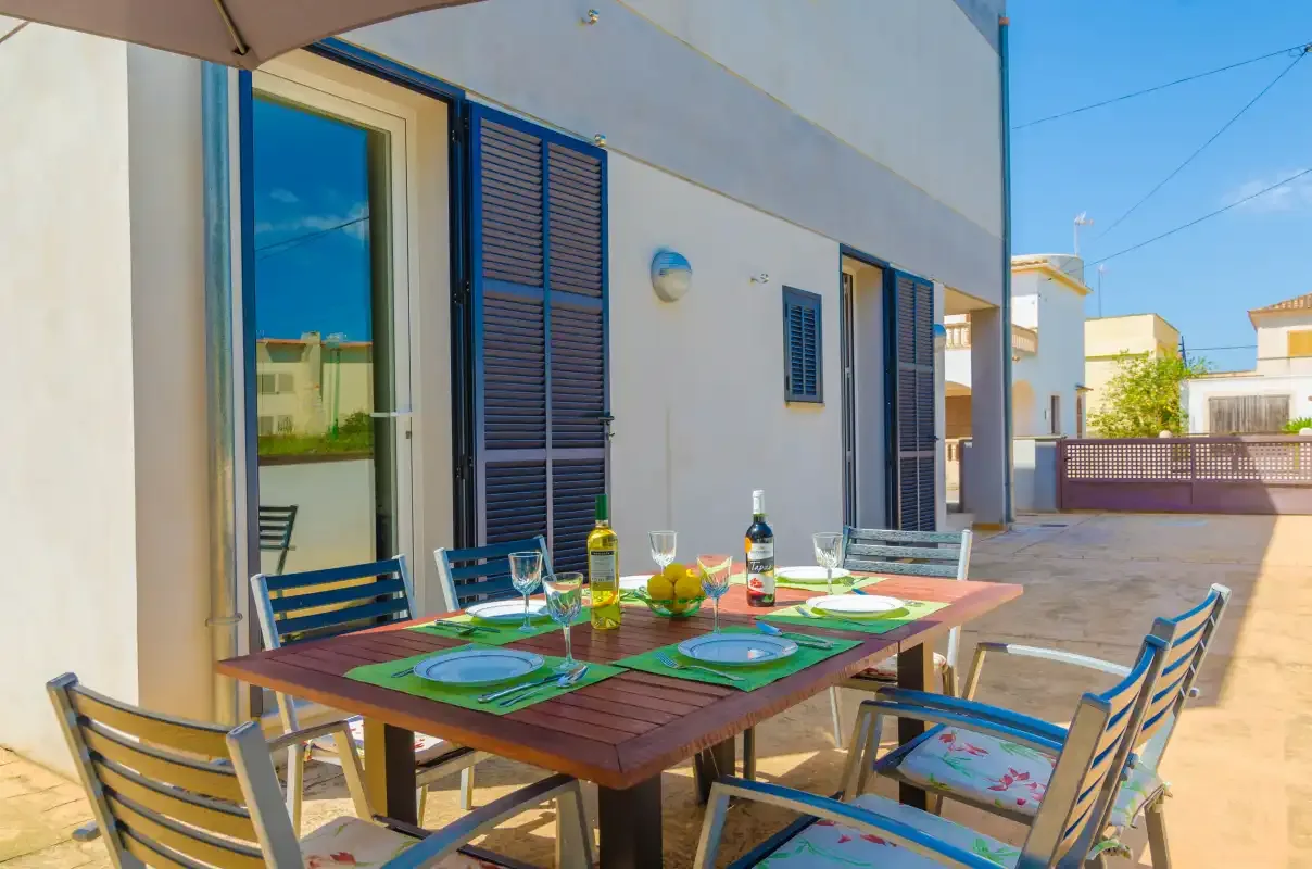 An outdoor dining area sits beside a modern building on a sunny terrace.