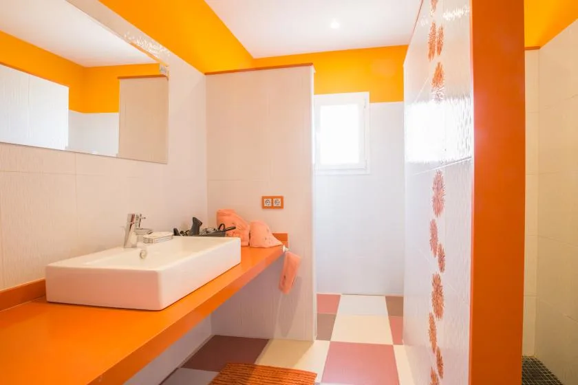 A bathroom with a sink on an orange counter and a tiled floor.