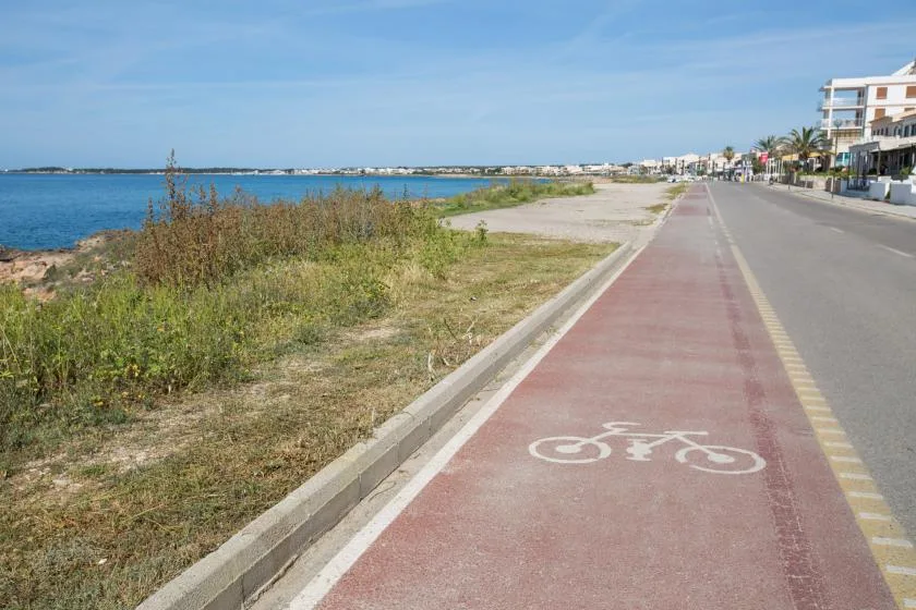 A seaside path with a marked bicycle lane runs beside the road.