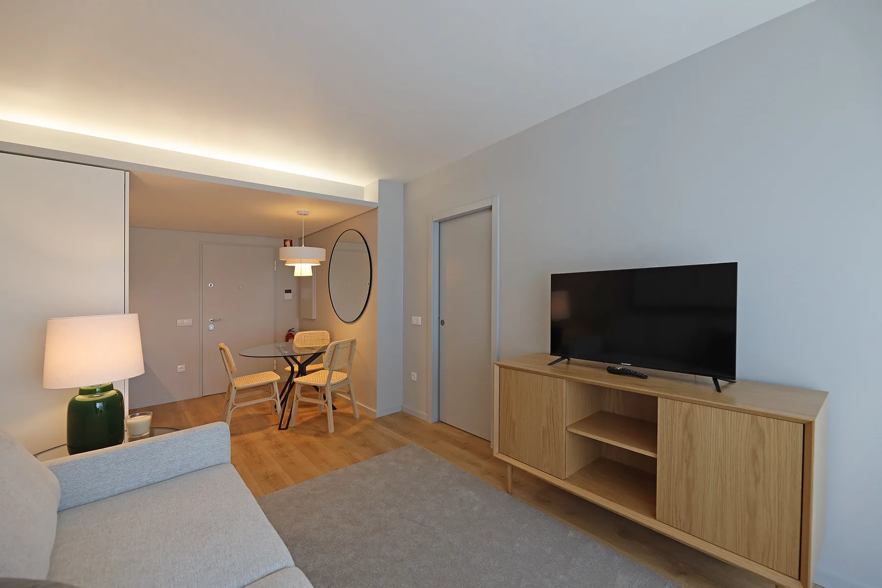 A living room with a television on a wooden cabinet and a dining area.