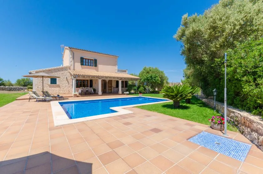 A house with a swimming pool and tiled patio under a clear blue sky.