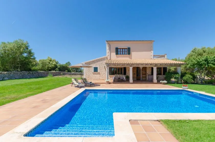 A swimming pool and tiled patio sit in front of a house.