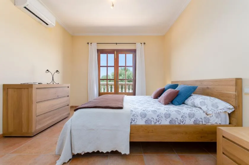 A bedroom with a wooden bed, patterned bedding, and a dresser.