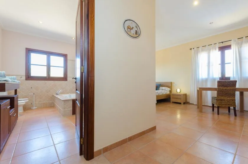 A bedroom and adjoining bathroom are visible, with a bed and window.