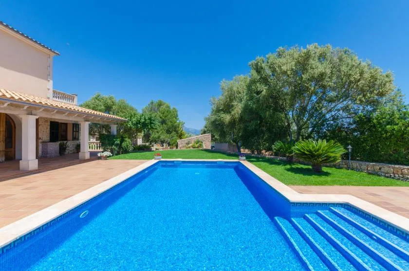 A swimming pool beside a paved patio, with steps at one end.
