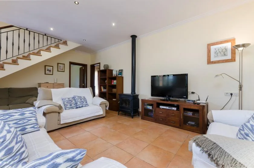 A living room with seating, a television, and a staircase.