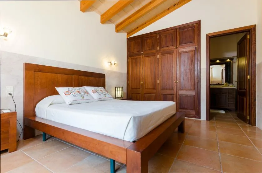 A bedroom with a wooden bed, built-in wardrobes, and exposed ceiling beams.