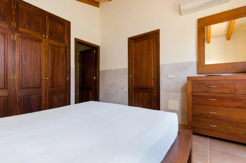 A bedroom with a large bed, wooden wardrobes, and a dresser.