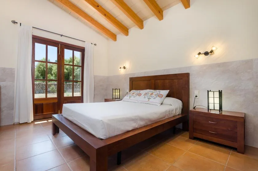 A bedroom with a wooden bed and French doors opening onto a garden.