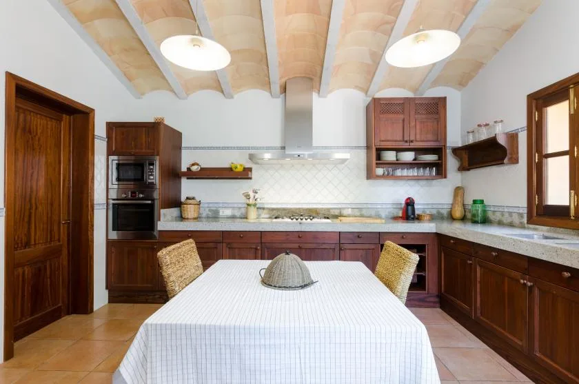 A spacious kitchen with dark wooden cabinetry and a dining table in the foreground.