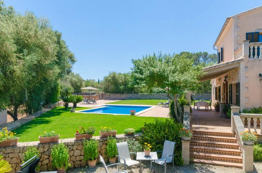 A landscaped garden surrounds a swimming pool beside a house.