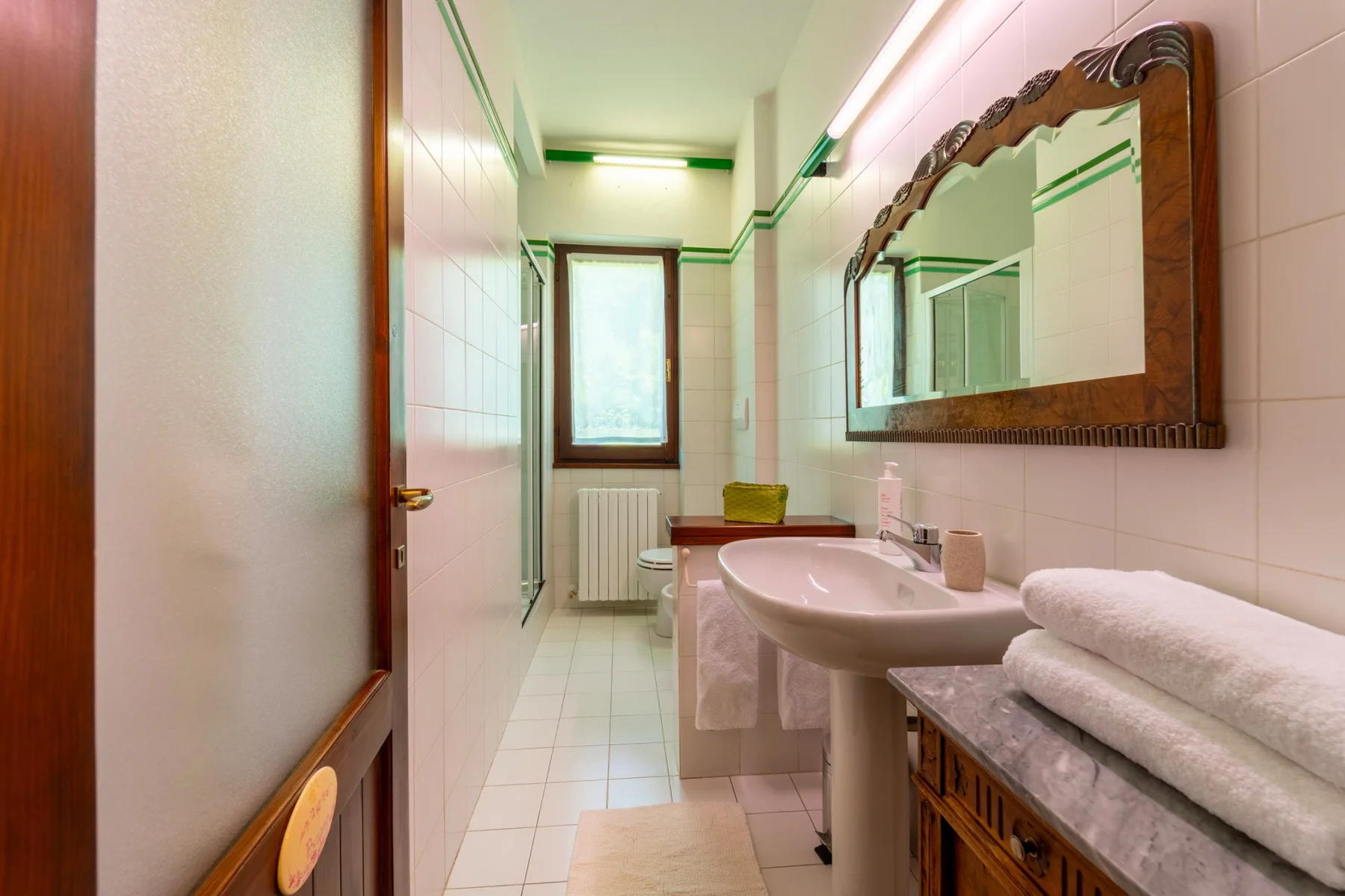A tiled bathroom with a sink, mirror, and folded towels.