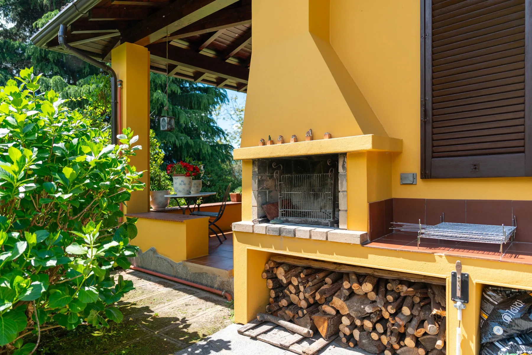 An outdoor patio with a built-in fireplace and stacked firewood.