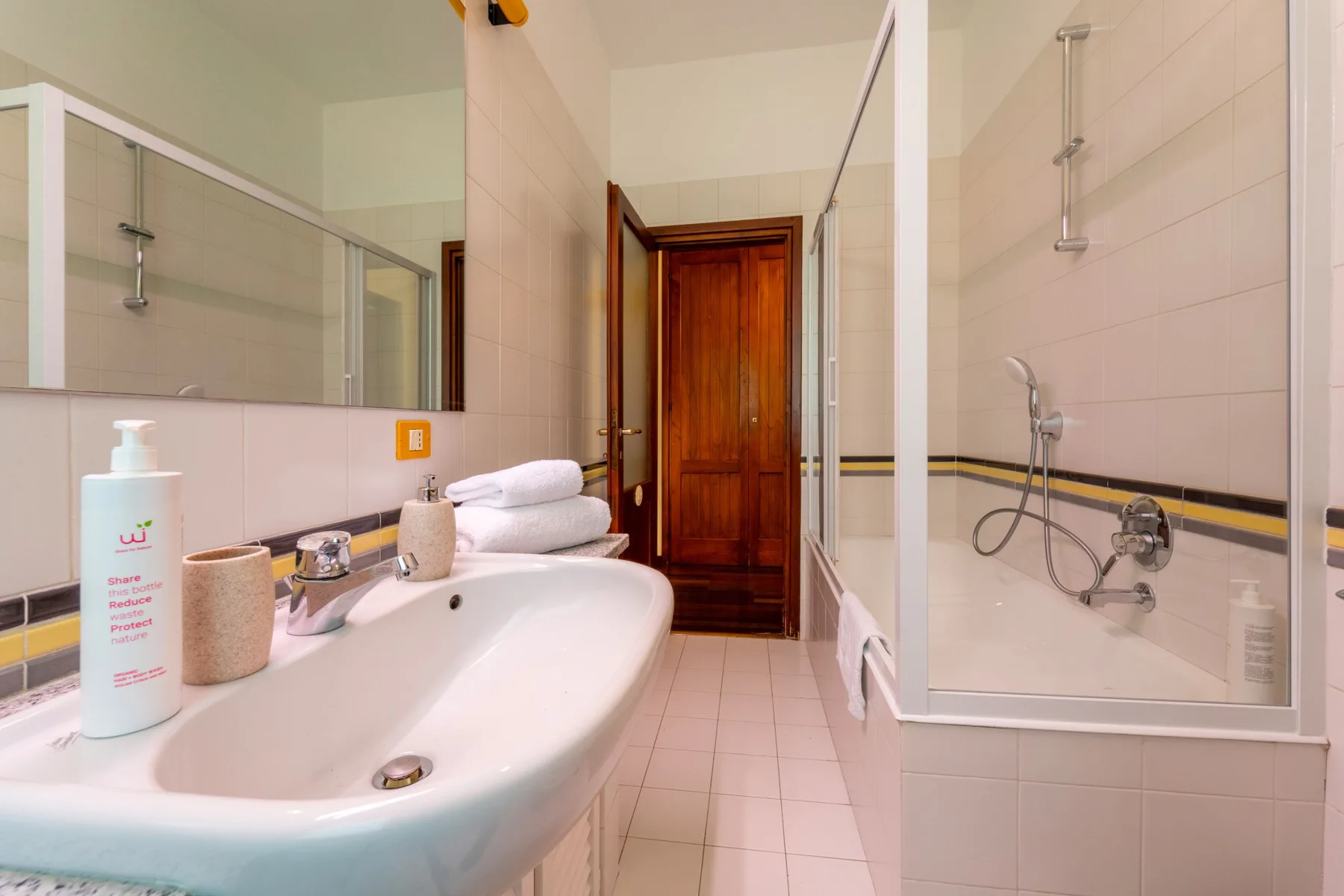 A tiled bathroom with a bathtub, sink, and wooden door.