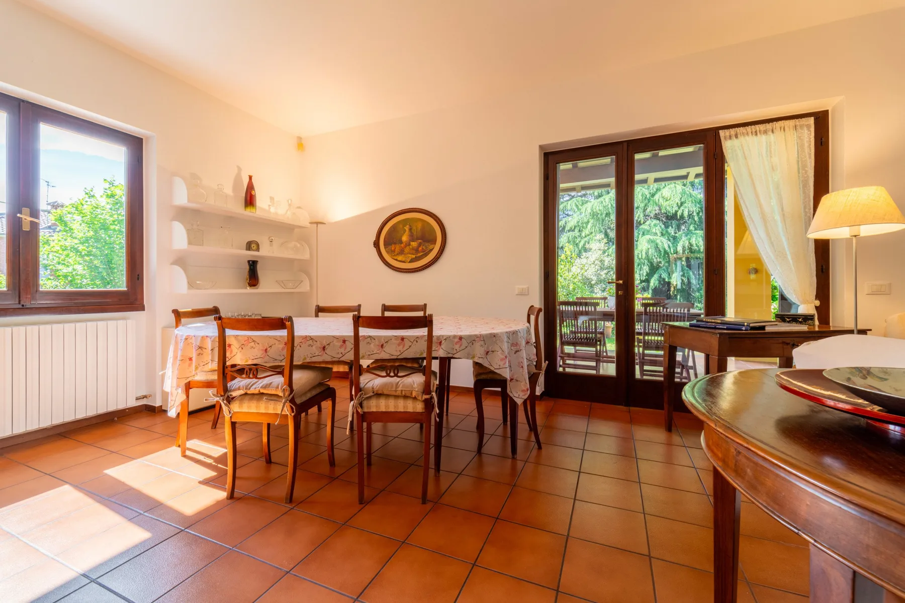 A dining area with a table and chairs beside glass doors opening to greenery.