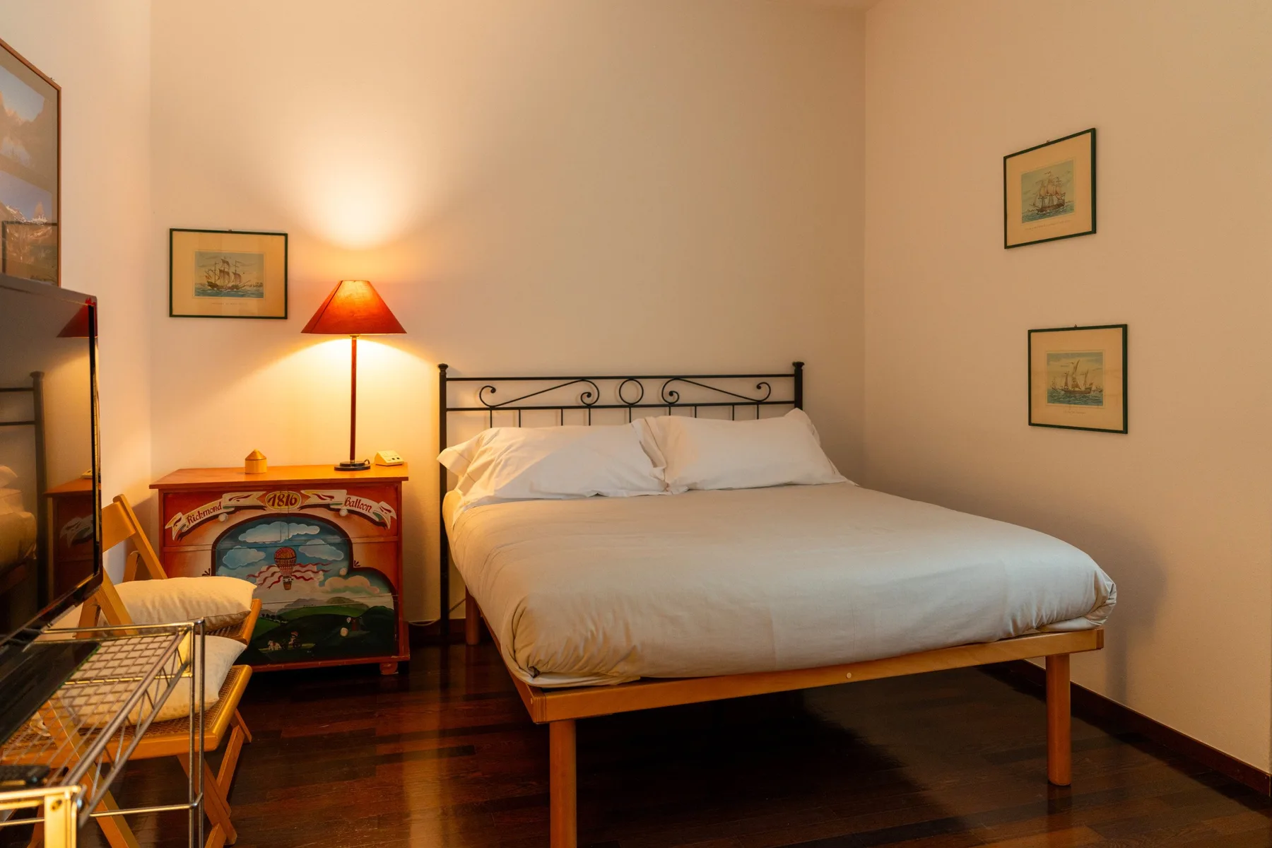 A bedroom with a neatly made bed and a lit bedside lamp.