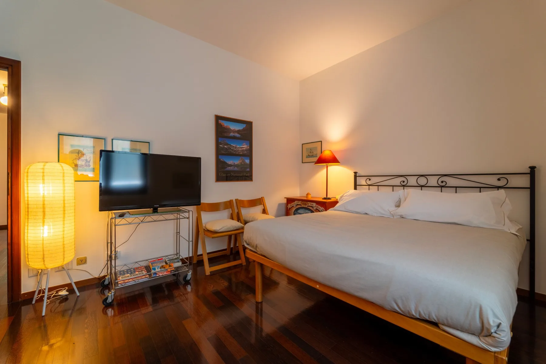 A bedroom with a bed, television, and warm lighting.