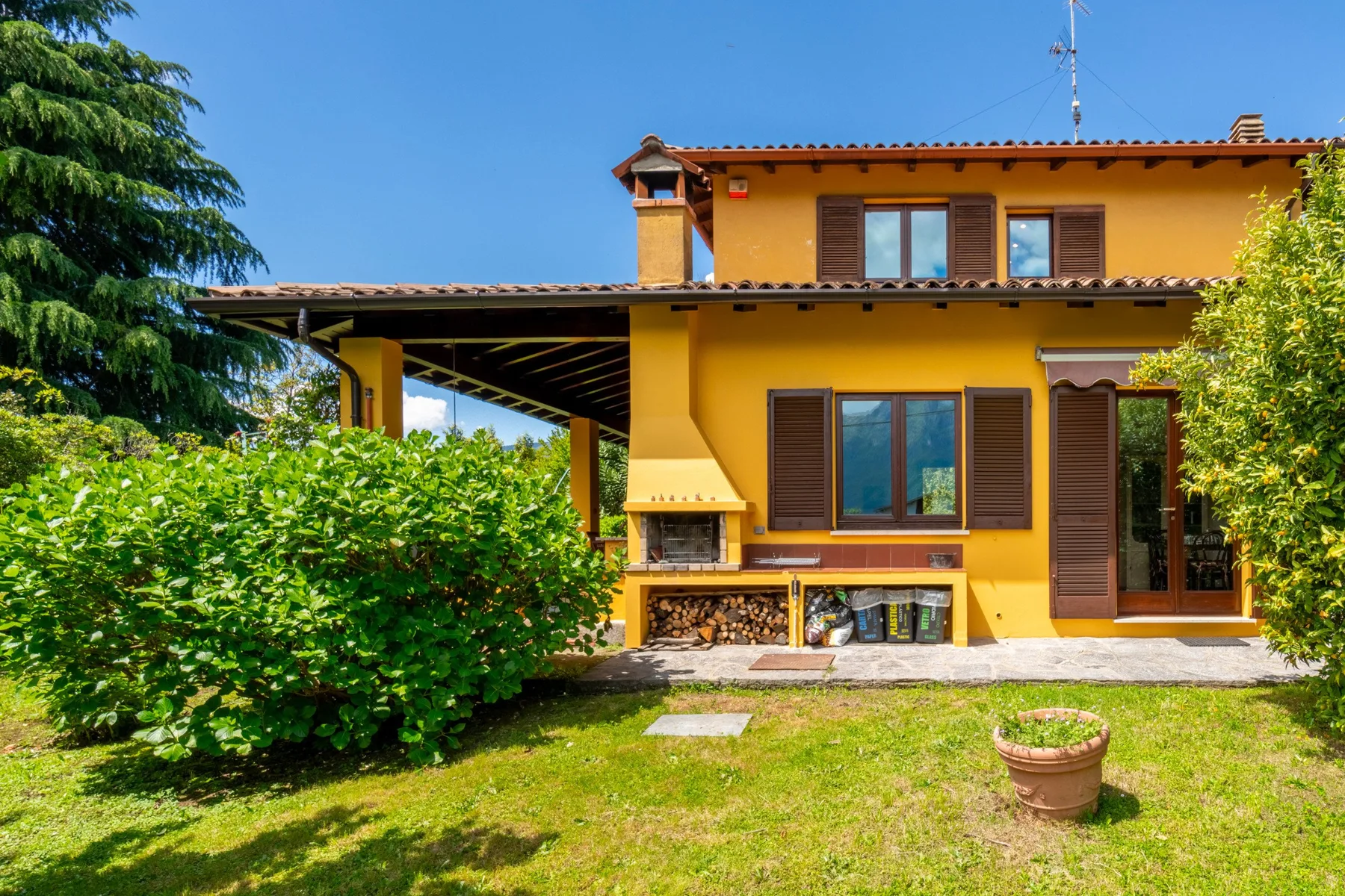 A yellow house faces a green lawn, with a covered patio beside it.