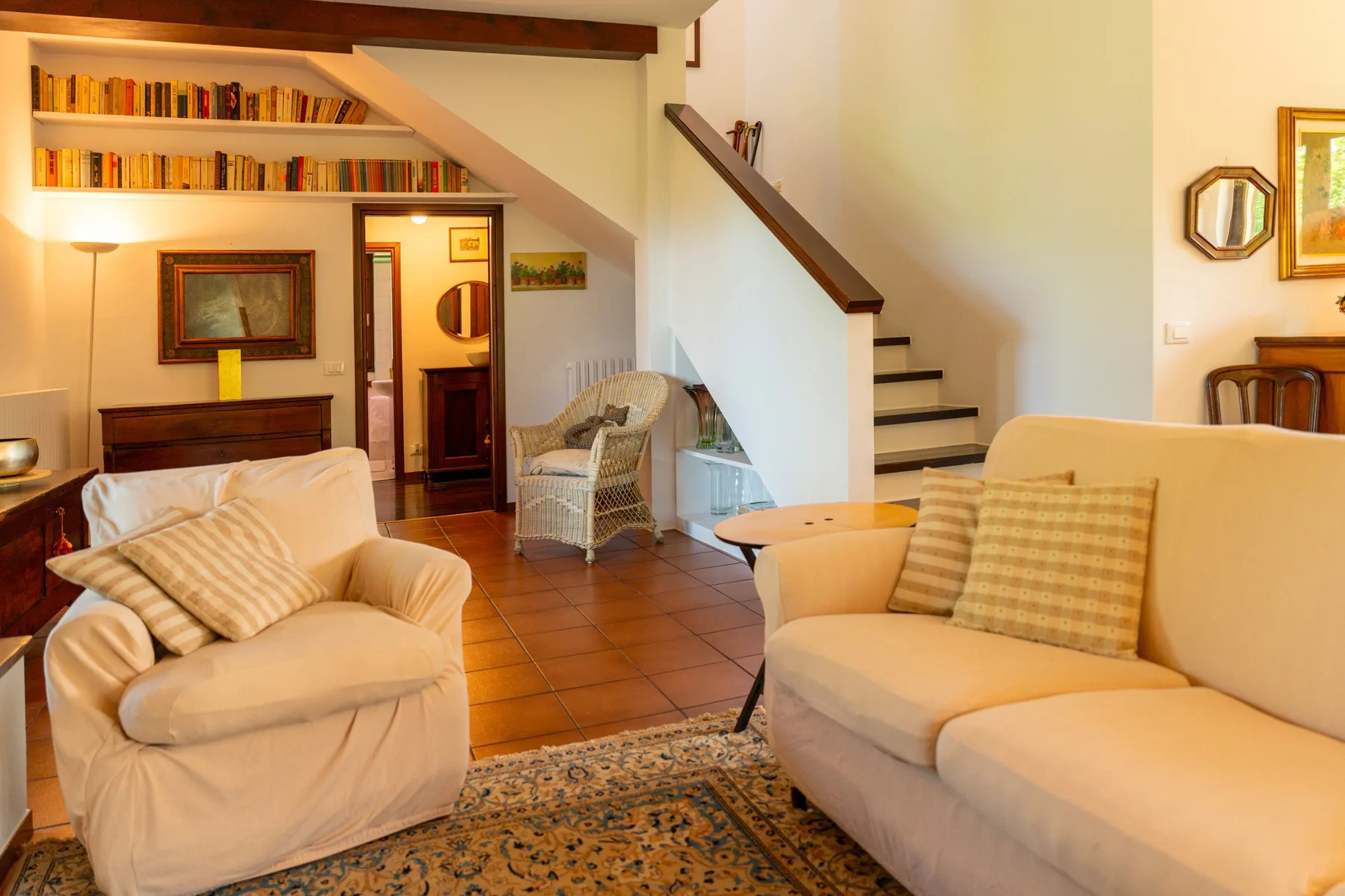 A living room with two seating areas, a rug, and stairs along the wall.