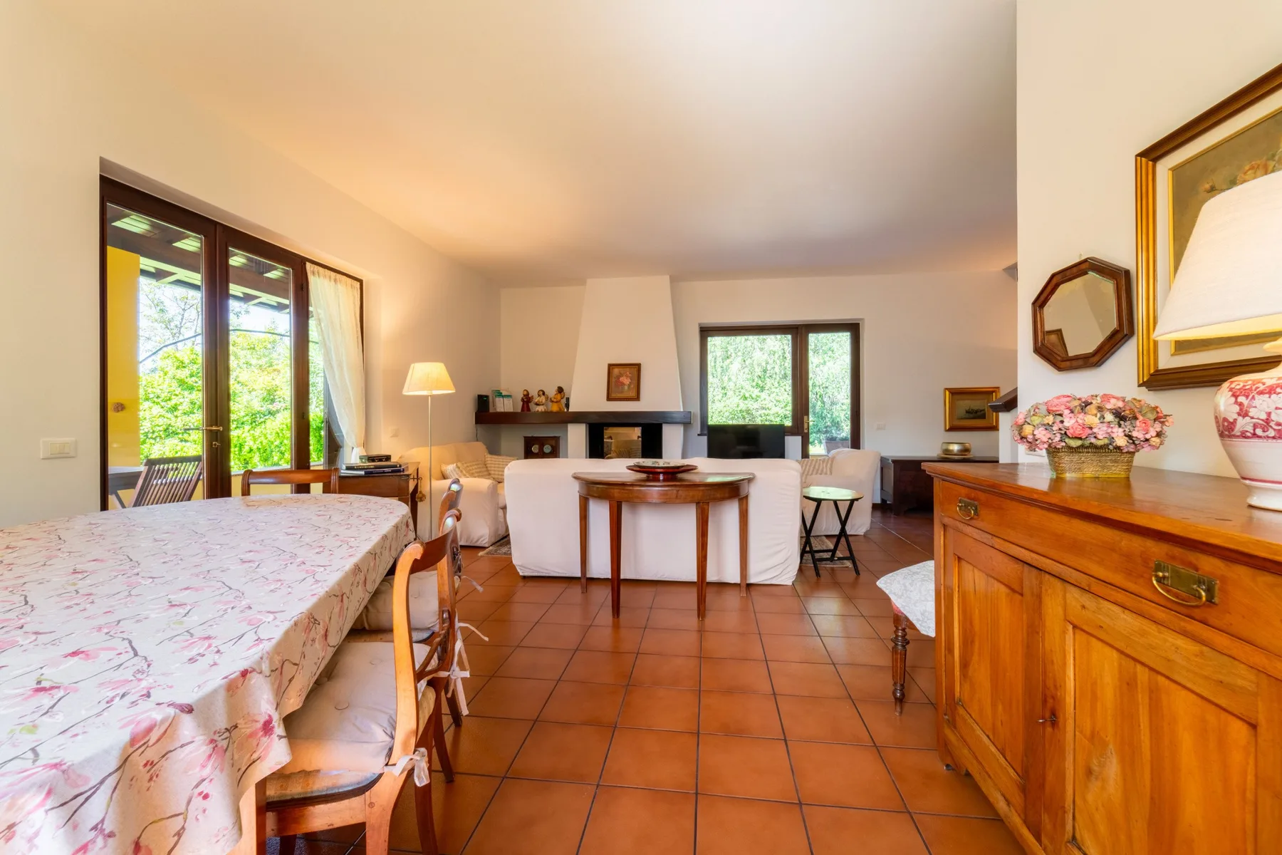 A bright dining and living area with a set table and fireplace.
