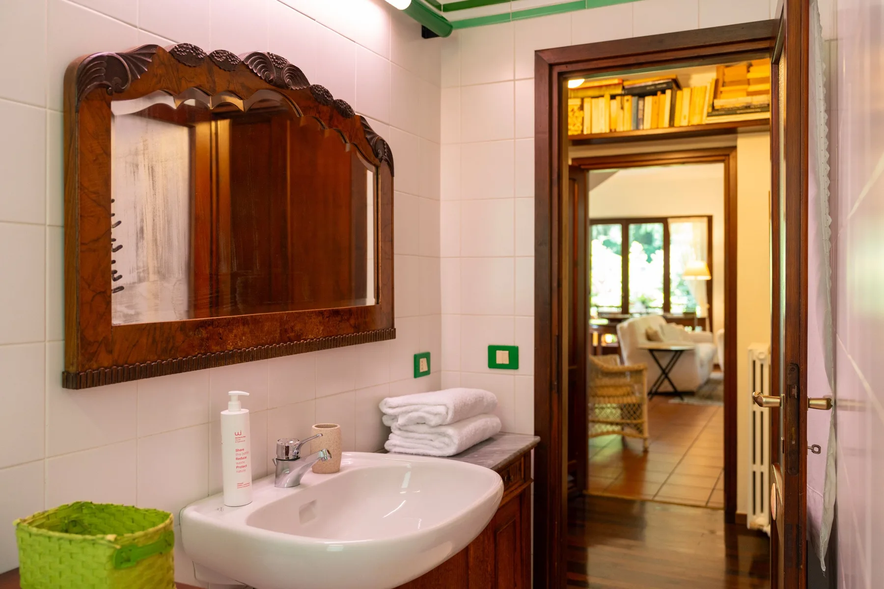 A tiled bathroom with a sink and an open doorway into a bright room.