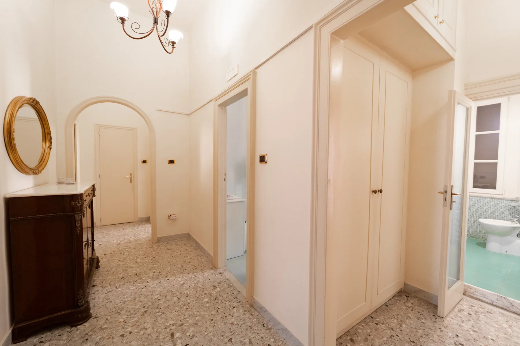 A bright interior hallway with several doorways and a patterned floor.