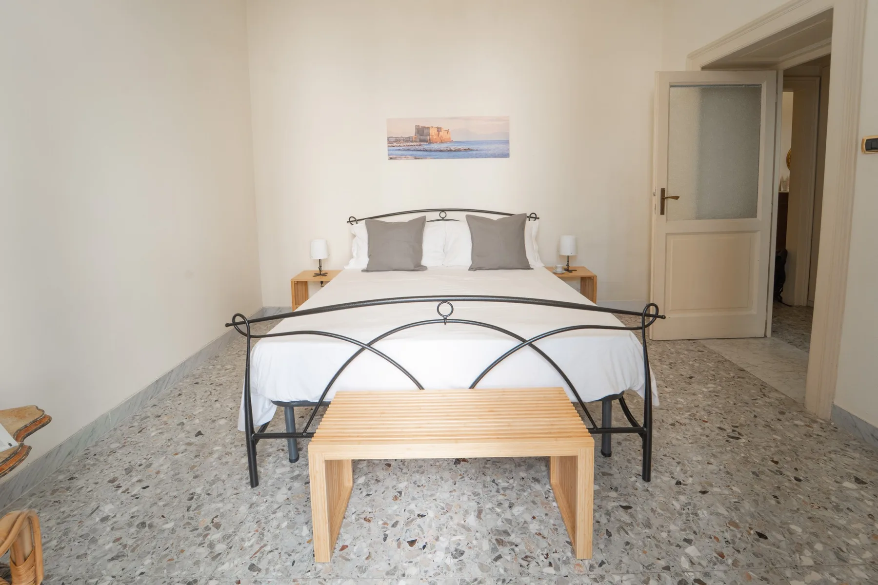 A bedroom with a double bed, bedside tables, and a small bench at the foot.