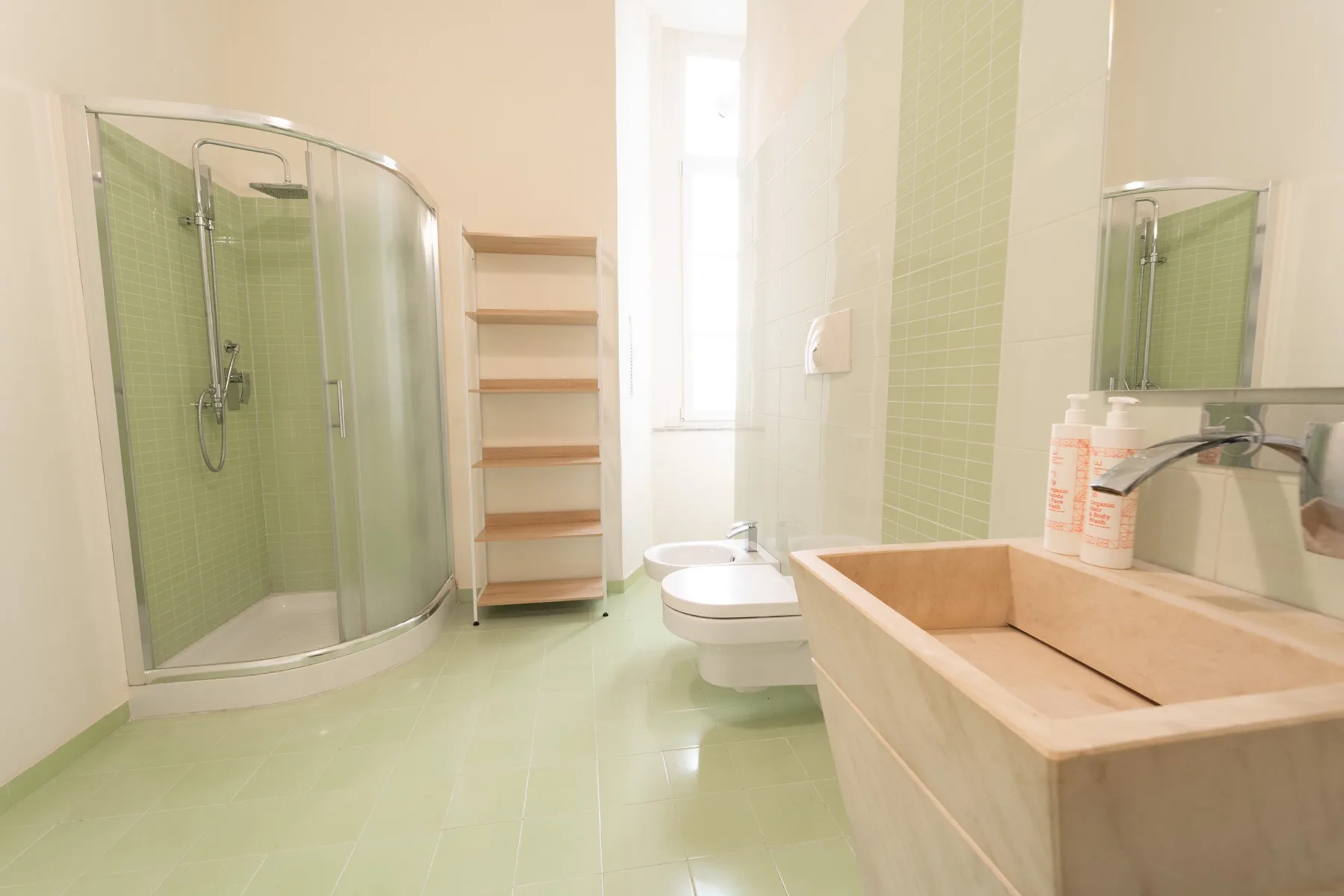 A bathroom with a glass shower, toilet, and a large sink.