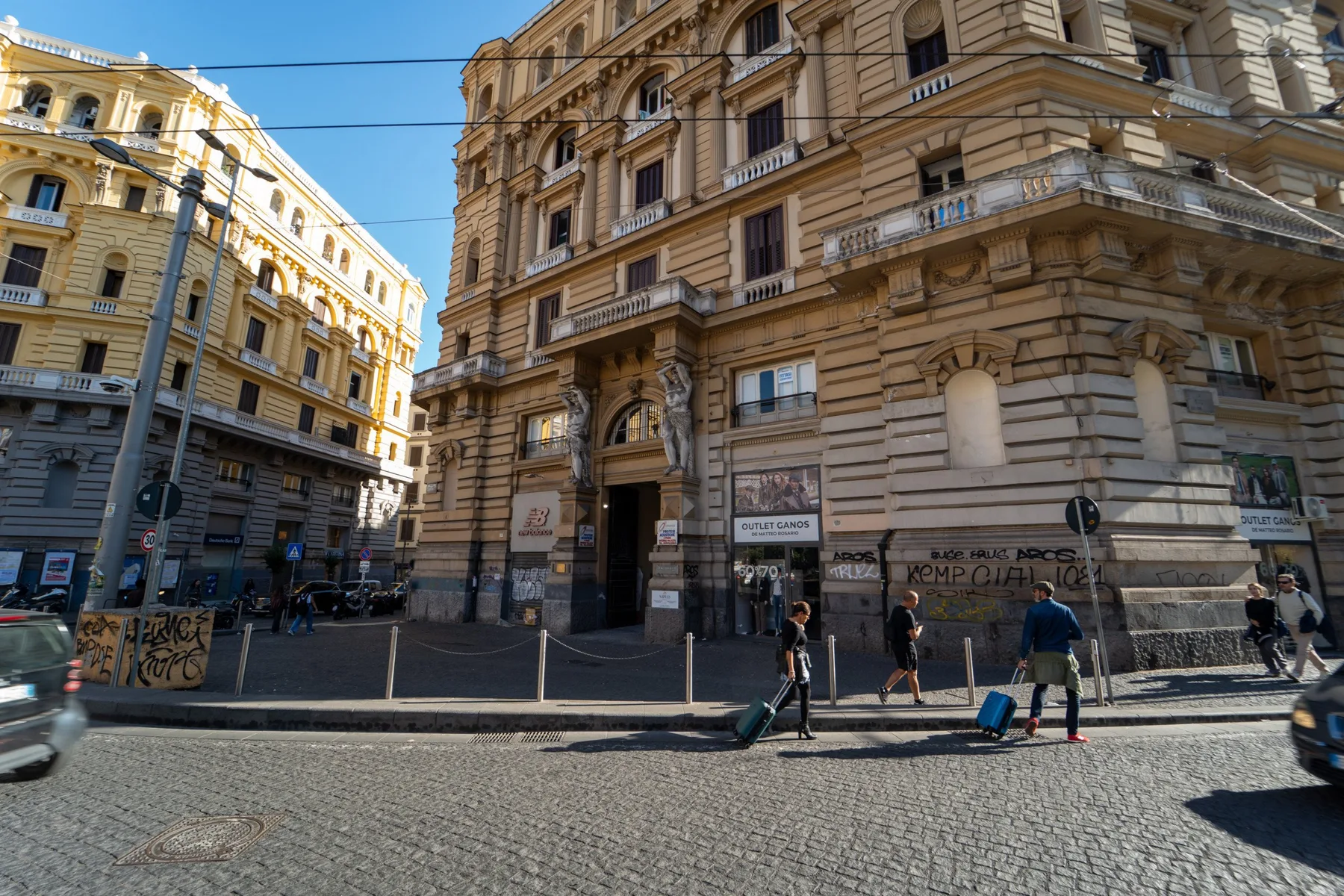 A cobblestone city street lined with ornate stone buildings and pedestrians.