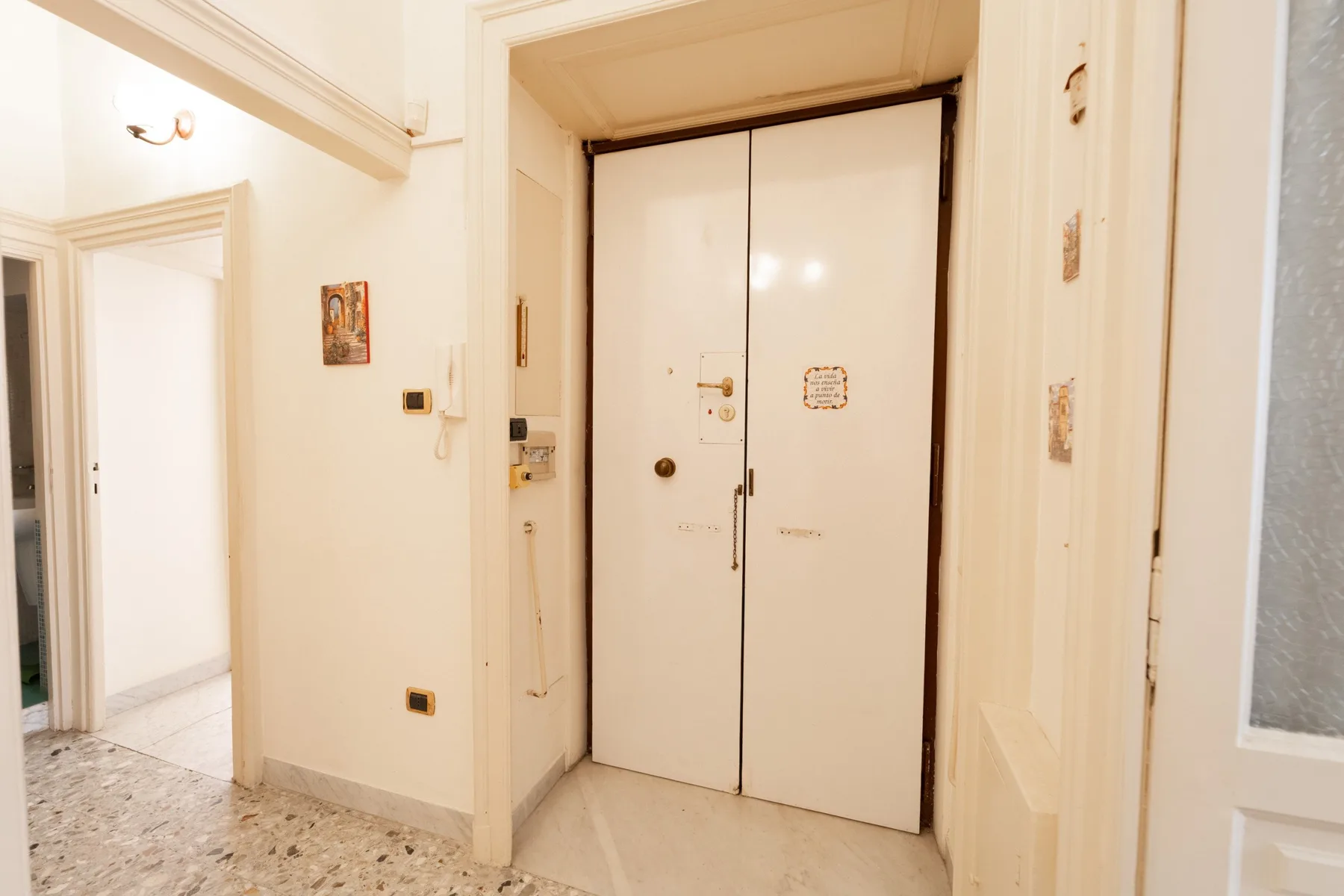 A bright interior hallway with closed double doors and a tiled floor.