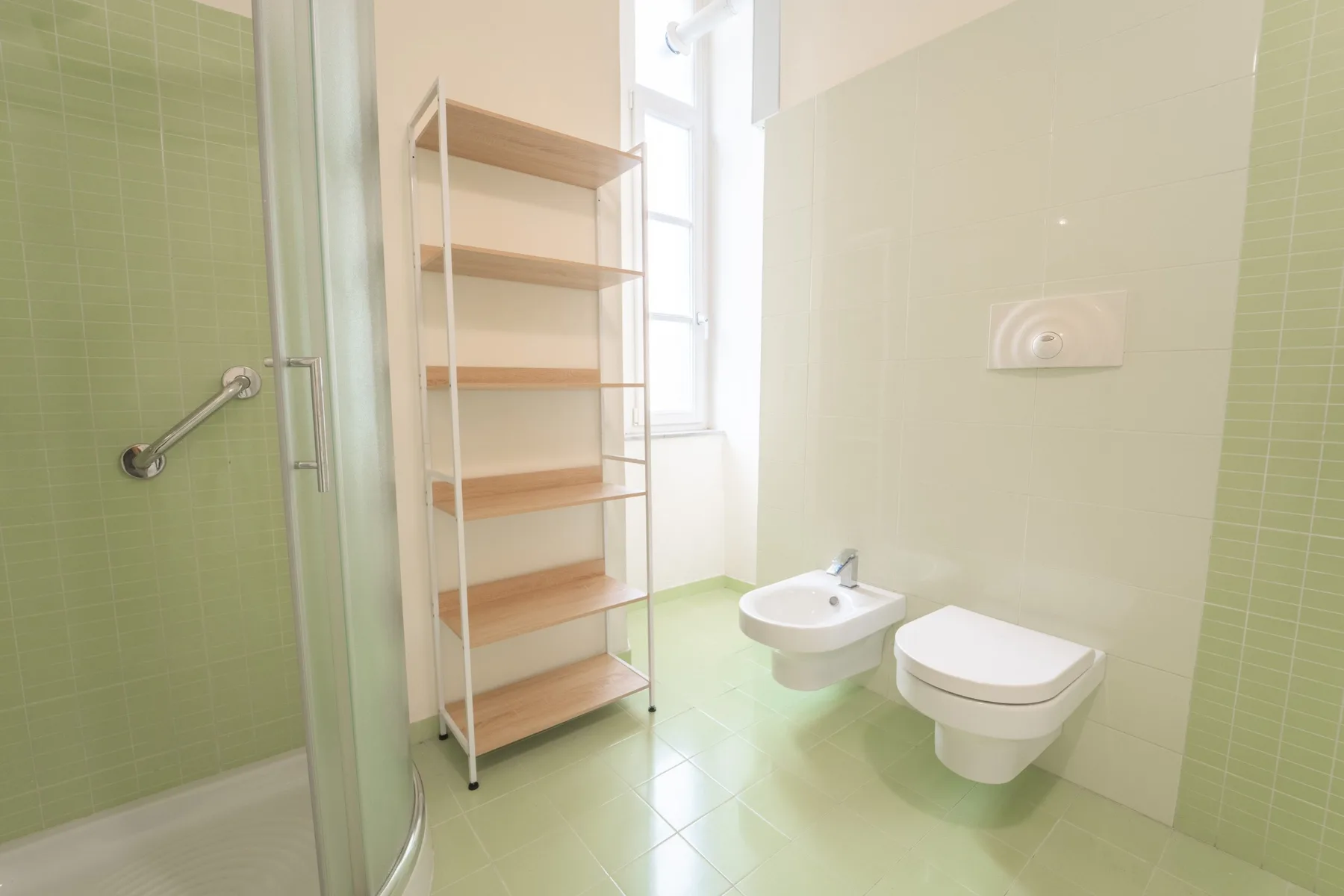 A bright bathroom with a shower, wall-mounted sink, and open shelving.