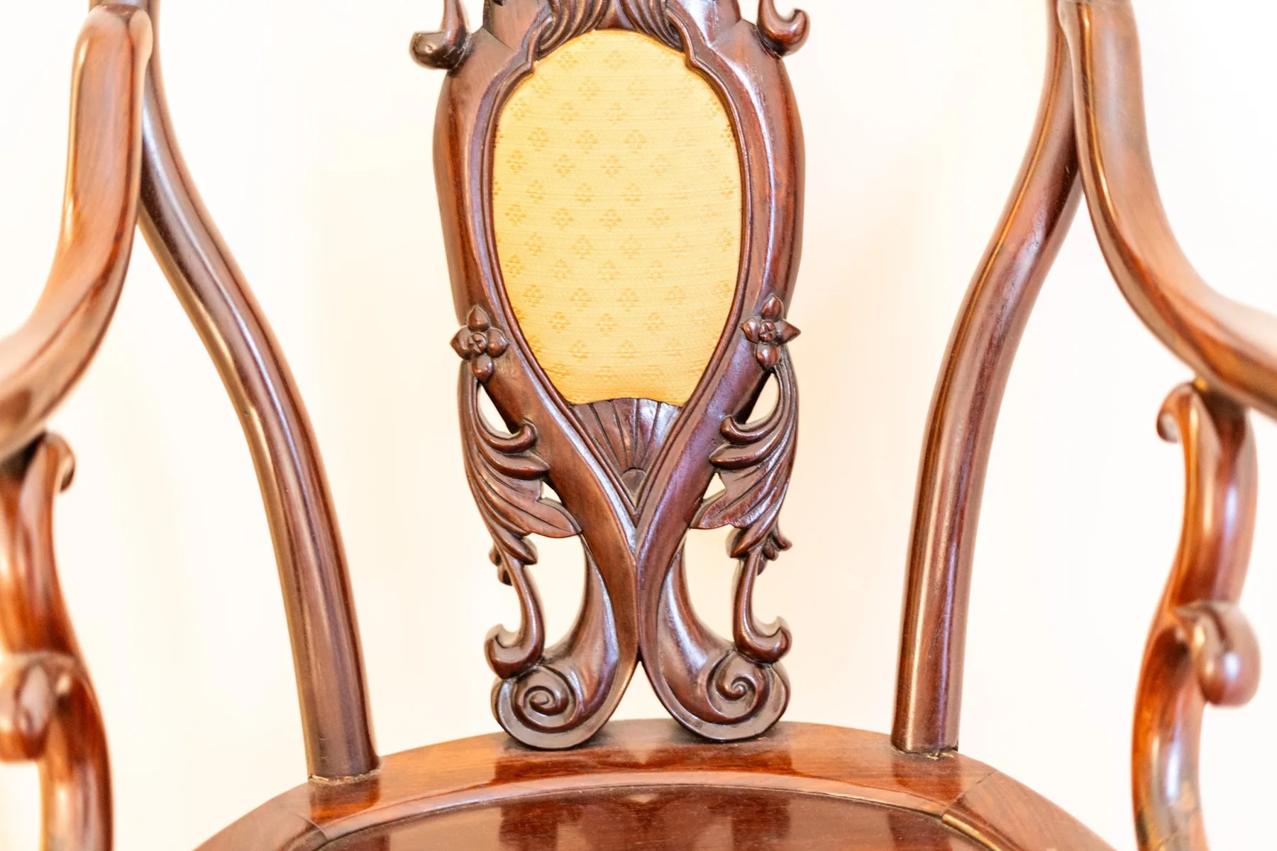 An ornate wooden chair with a carved back and upholstered center.