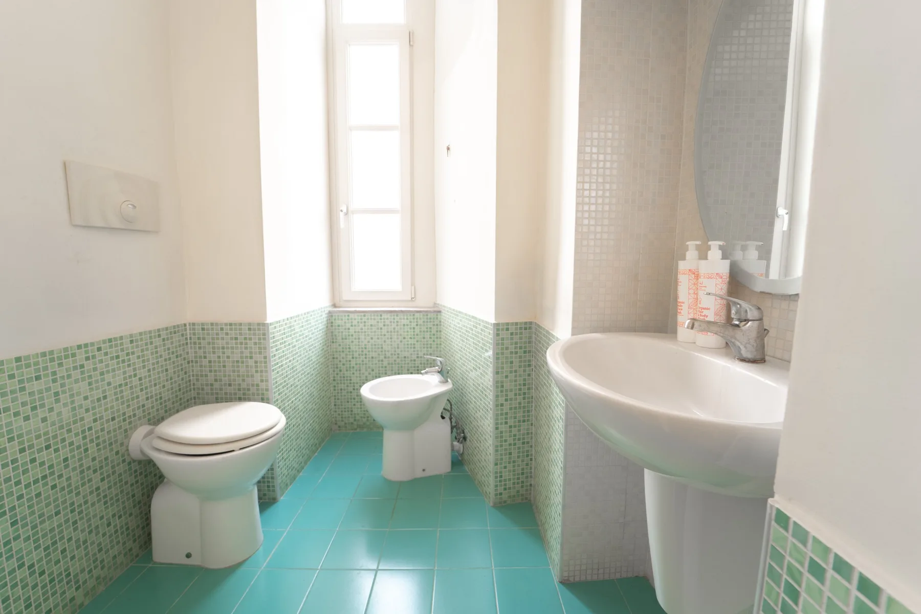 A bright bathroom with a toilet, bidet, and sink.