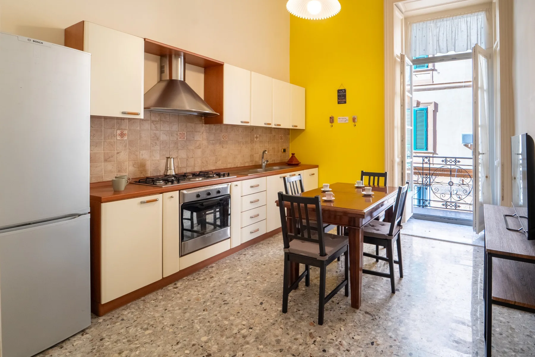 A kitchen and dining area with white cabinets and a wooden table.