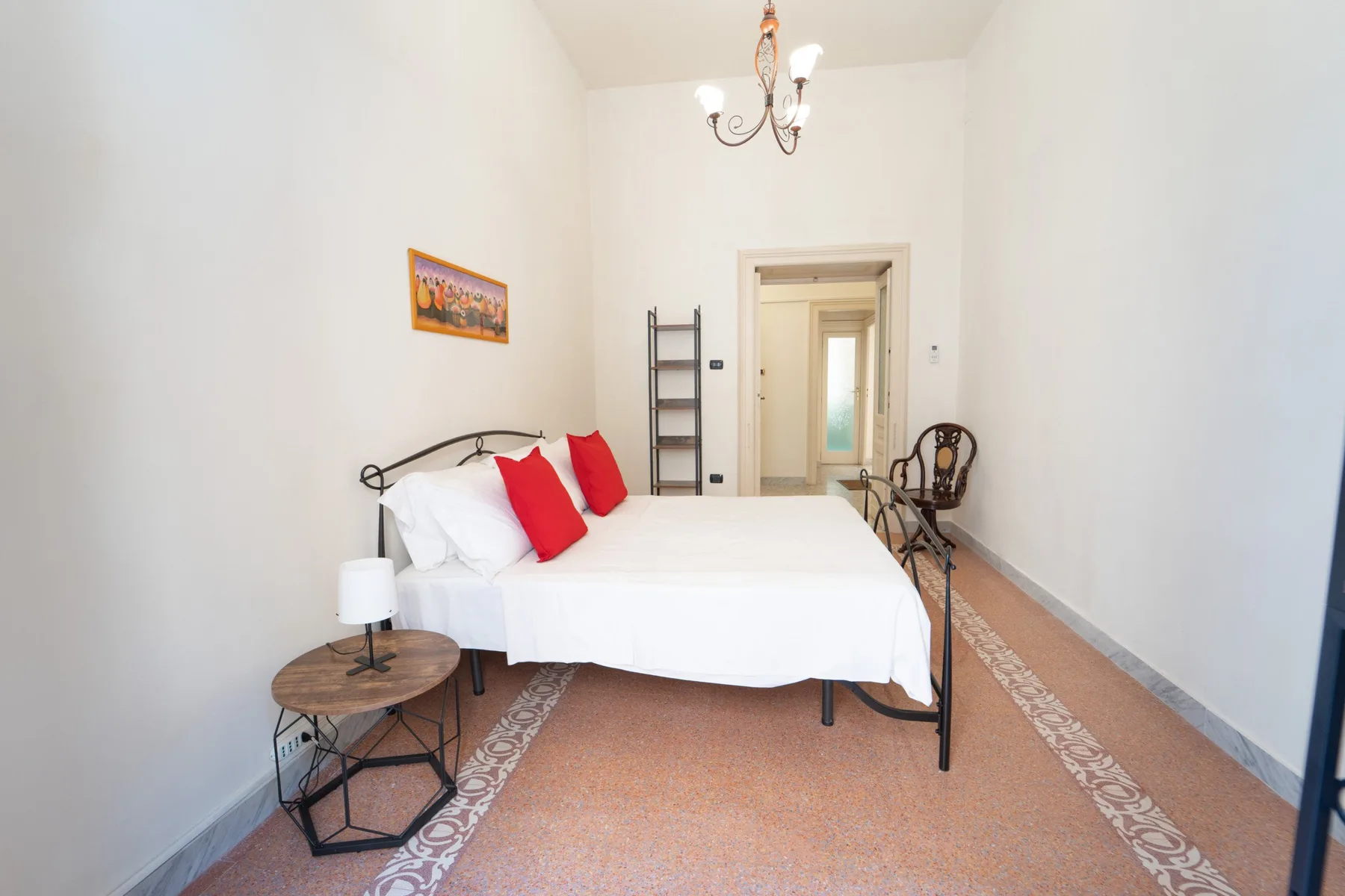 A bedroom with a bed, a small side table, and a doorway at the back.