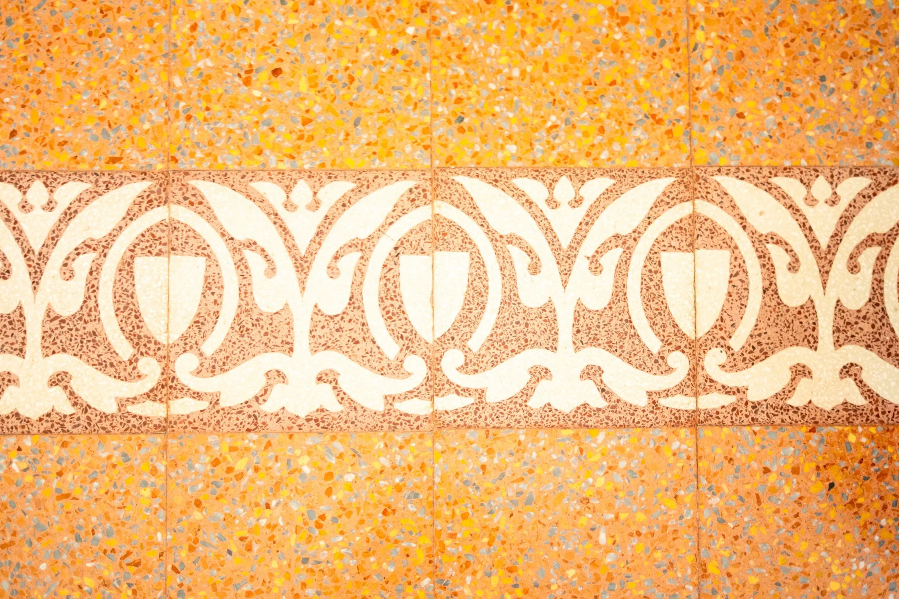 Decorative patterned tiles form a horizontal band across a speckled orange tiled surface.