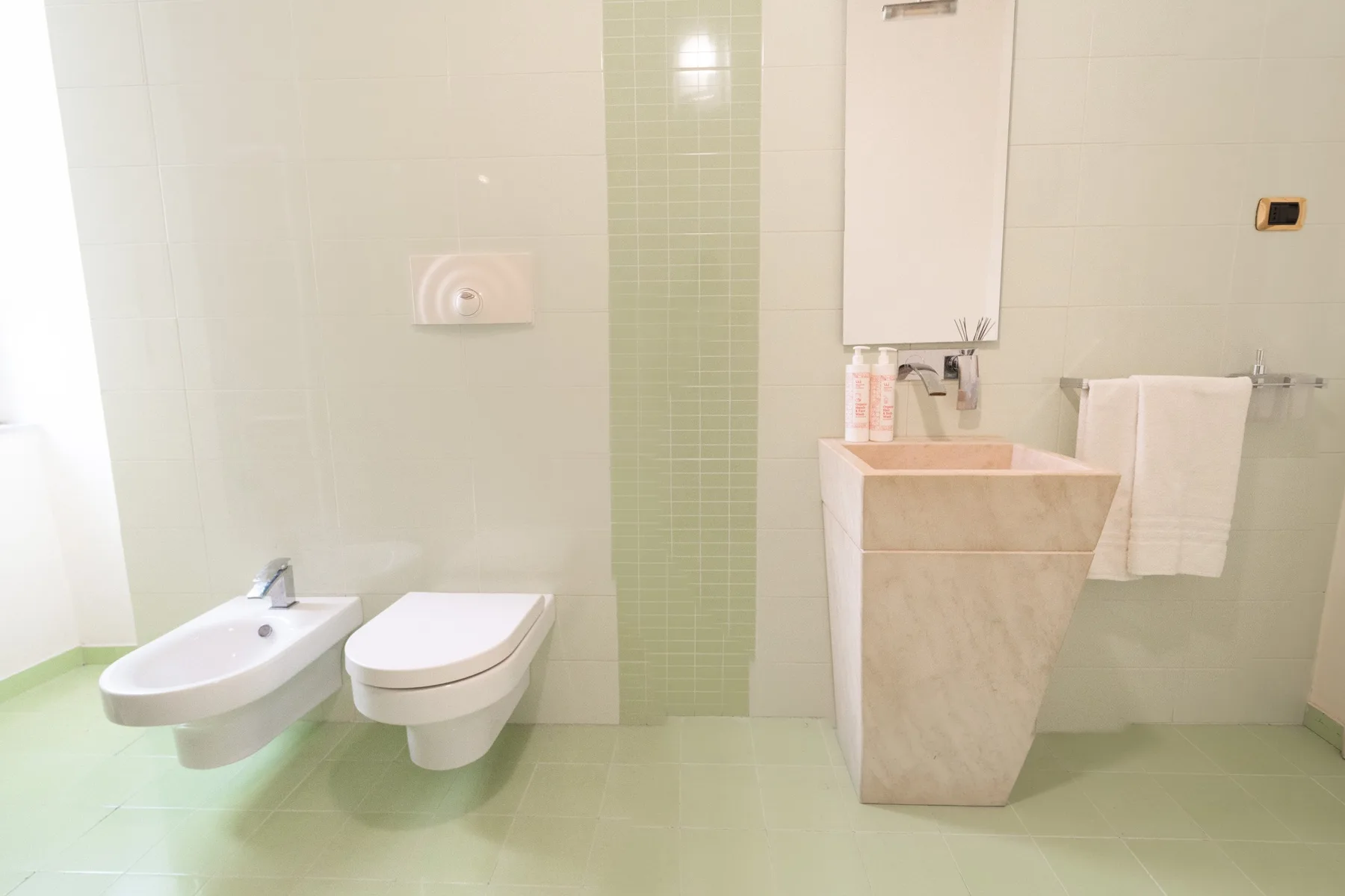 A tiled bathroom with a sink, toilet, and freestanding basin.