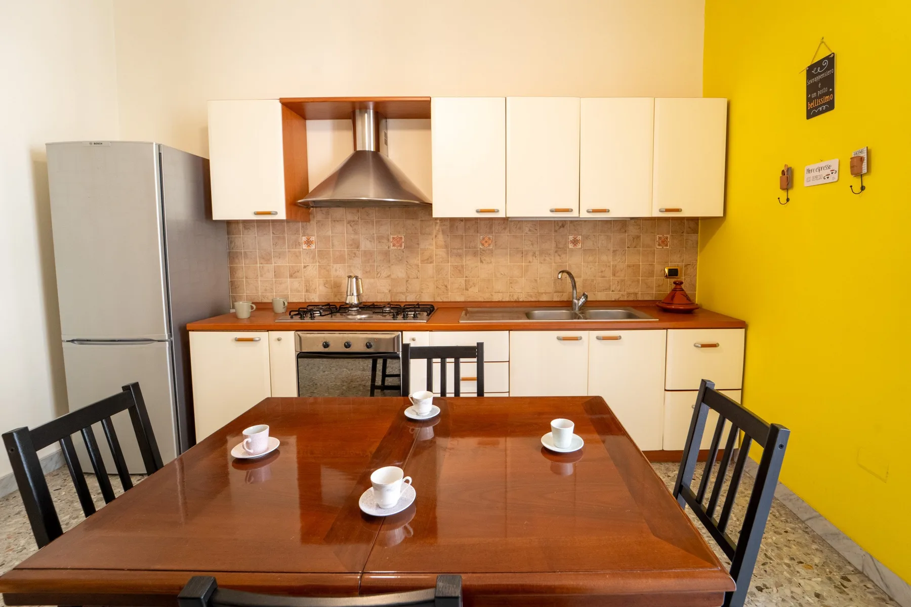 A kitchen and dining area with a wooden table set in front of the cabinets.