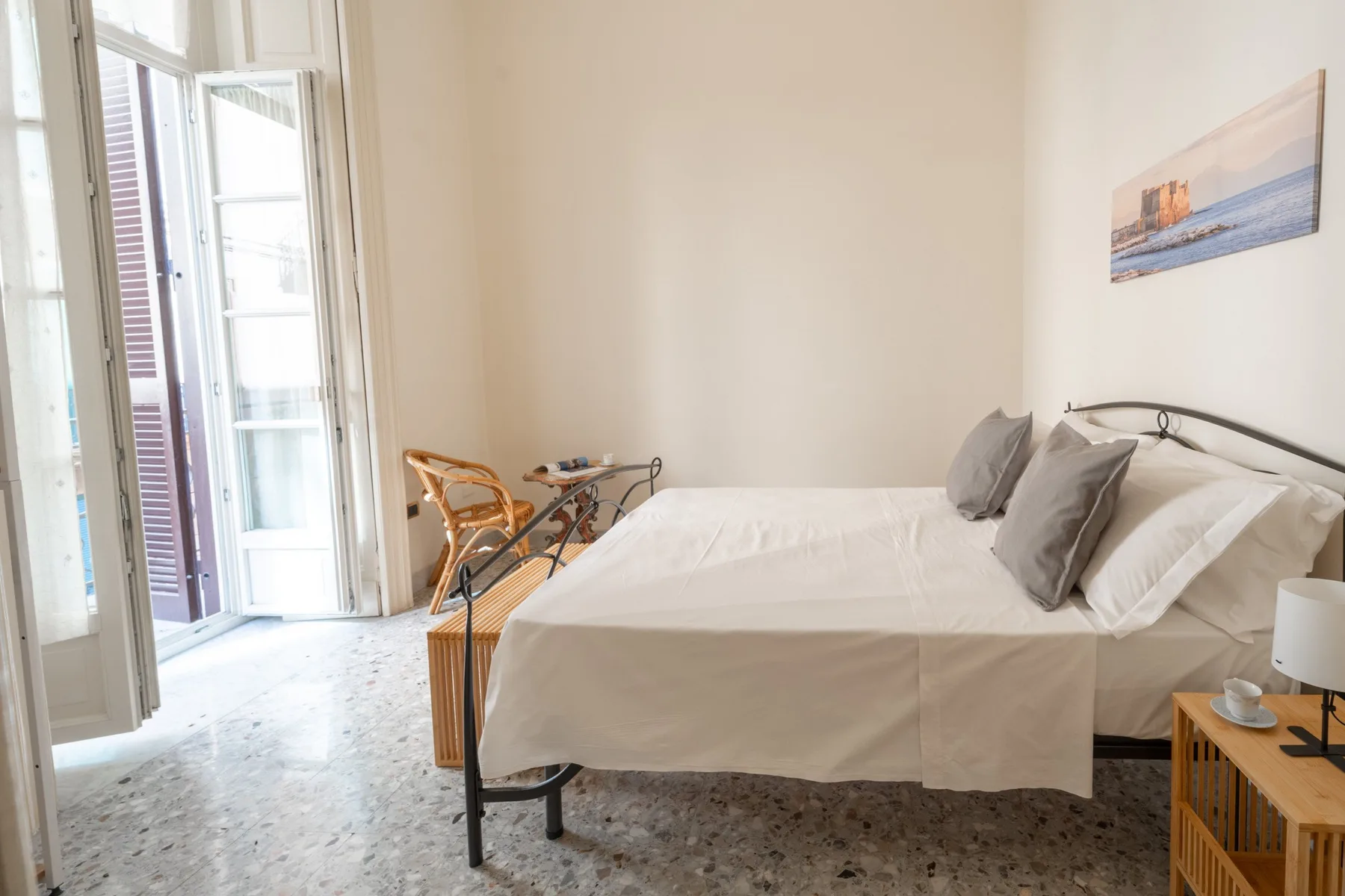 A bright bedroom with a neatly made bed and tall windows.
