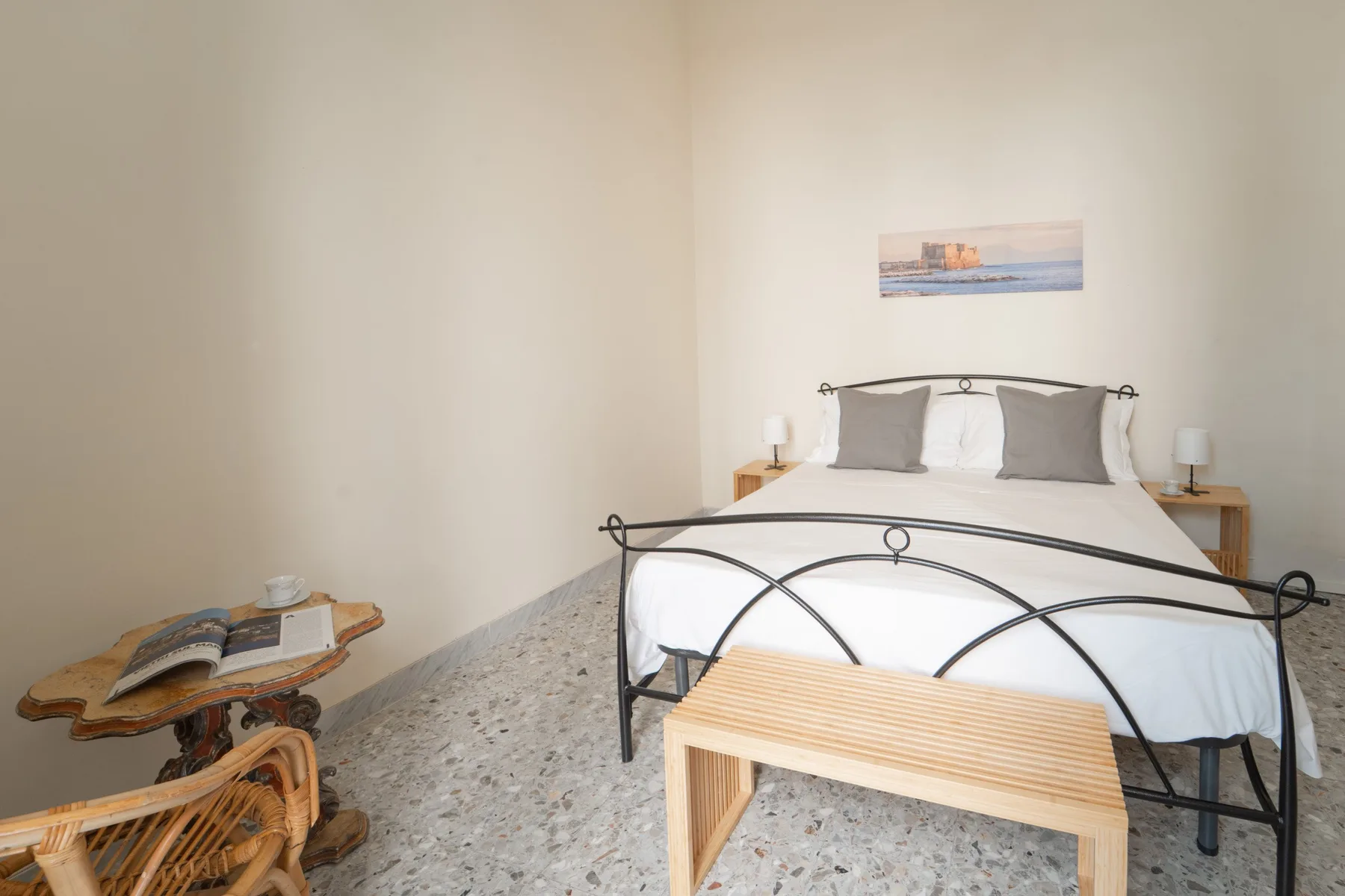 A bright bedroom with a bed, bedside tables, and a wooden bench.