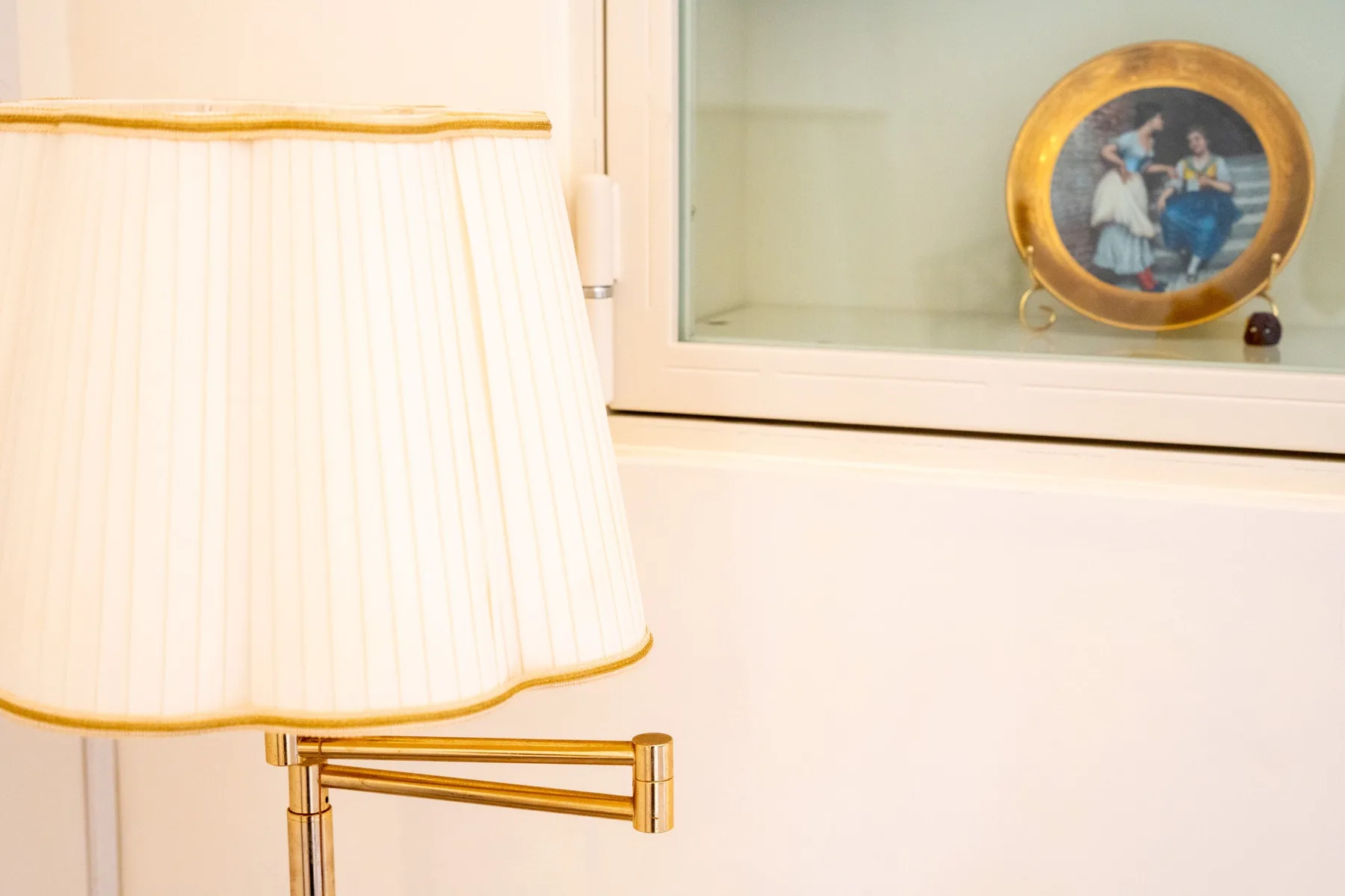 A table lamp sits beside a window with a decorative plate on the sill.