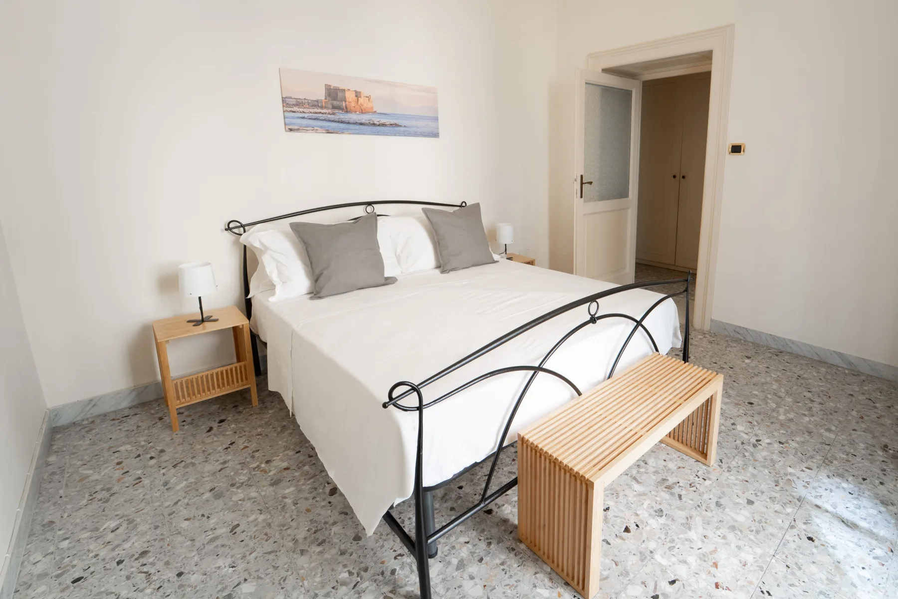 A bedroom with a neatly made bed and a wooden bench at its foot.