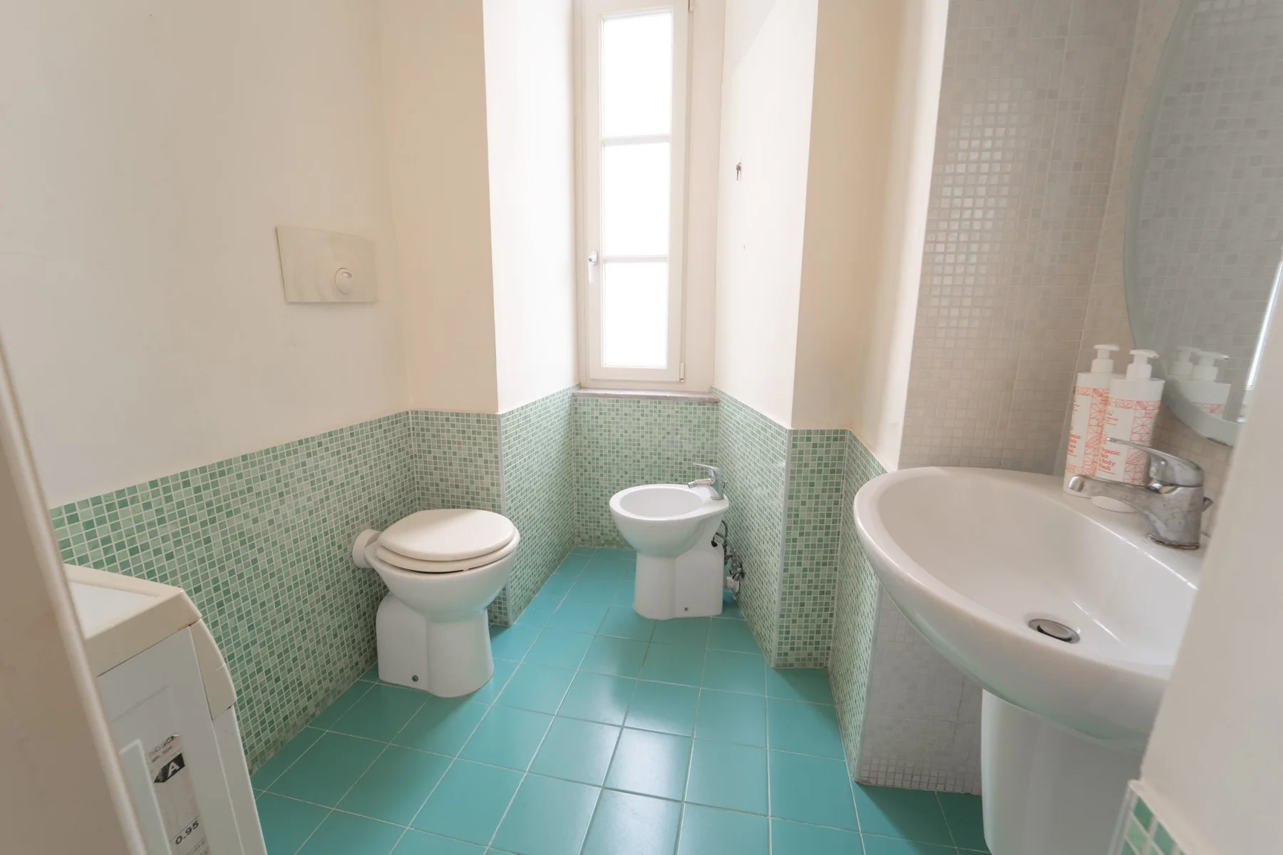 A bathroom with a toilet, sink, and tiled floor.